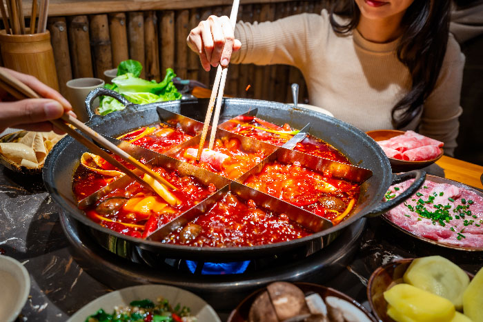 Turistas compartiendo la comida y haciendo uso de los palillos tradicionales Chinos